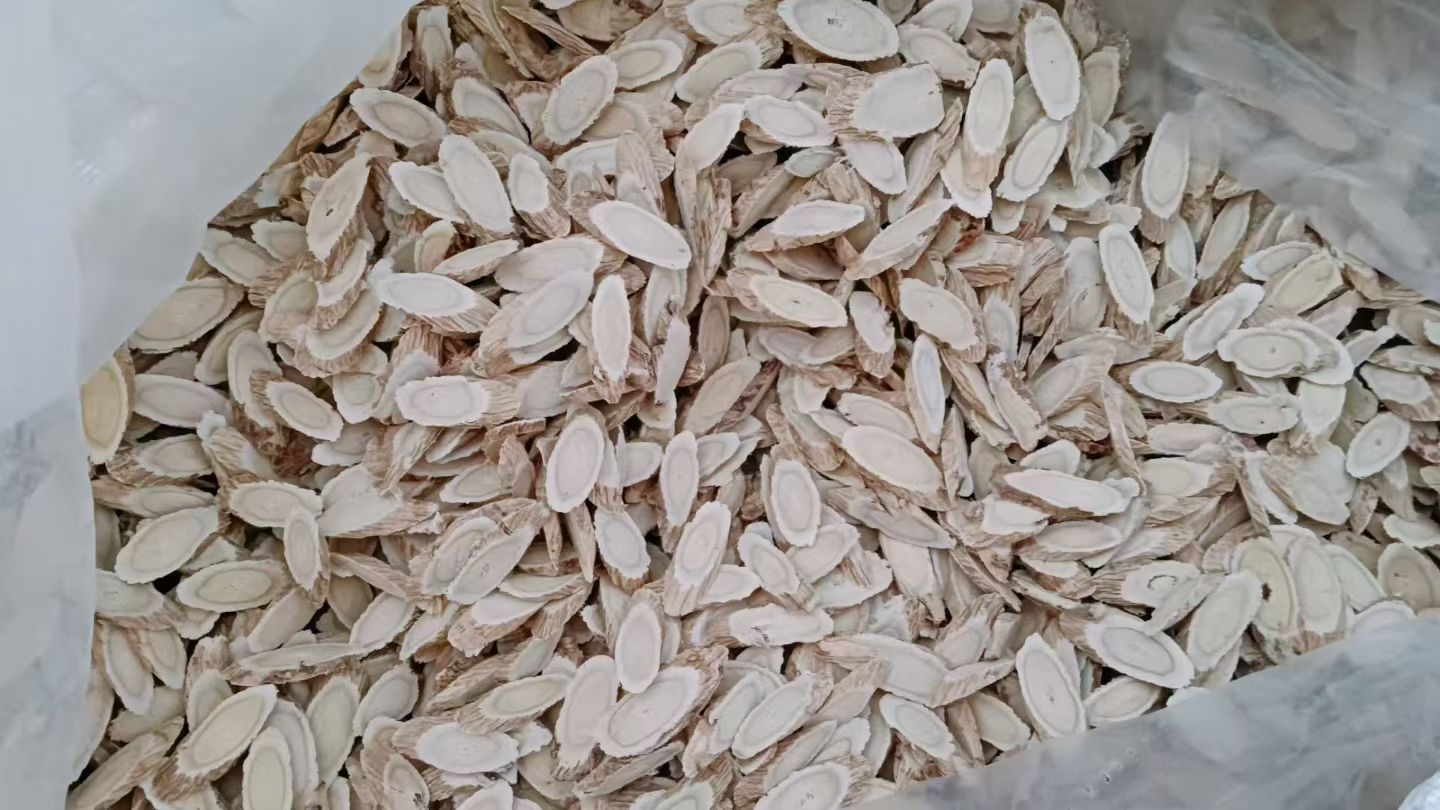 木制托盘上整齐摆放的黄芪饮片,呈片状结构,自然色泽,传统中药加工环境,干净整洁